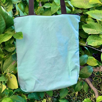 Totebag de algodón hecha a mano, con cierre de cremallera, con estampado artesanal de hojas de castaño y trasera de loneta verde turquesa.
